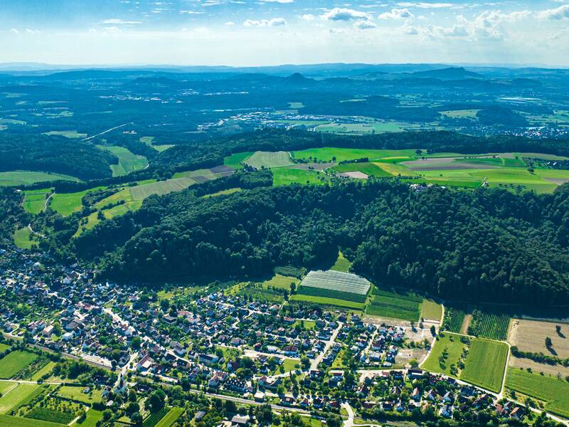 Luftaufnahme von Stahringen, eingebettet in einer grünen Hügellandschaft mit Feldern und Wald.