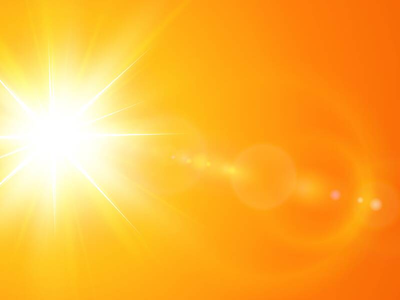 Ein hell leuchtender, strahlender Sonnenlichtfleck vor einem orangefarbenen Hintergrund.