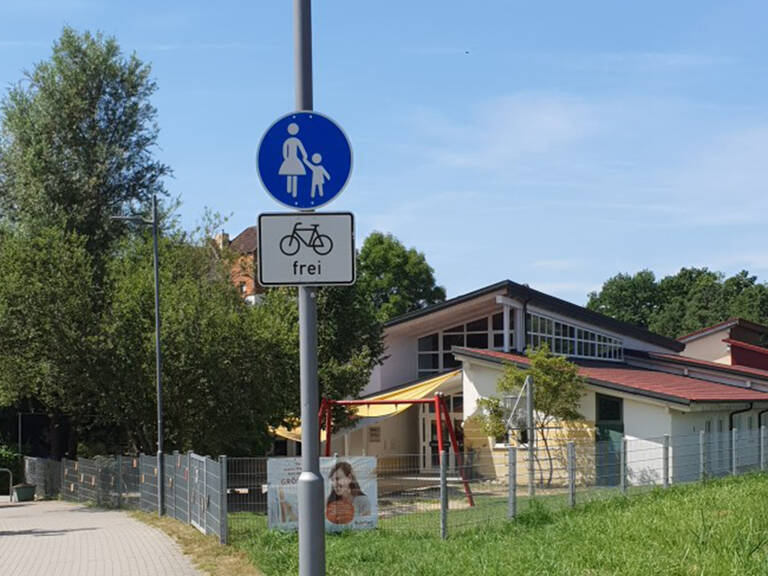 Ein Schild, das einen Gehweg für Fußgänger mit Kinderwagen symbolisiert und darunter ein Schild mit der Aufschrift "Fahrrad frei" zeigt, steht neben dem Werner-Meßmer-Kinderhaus..