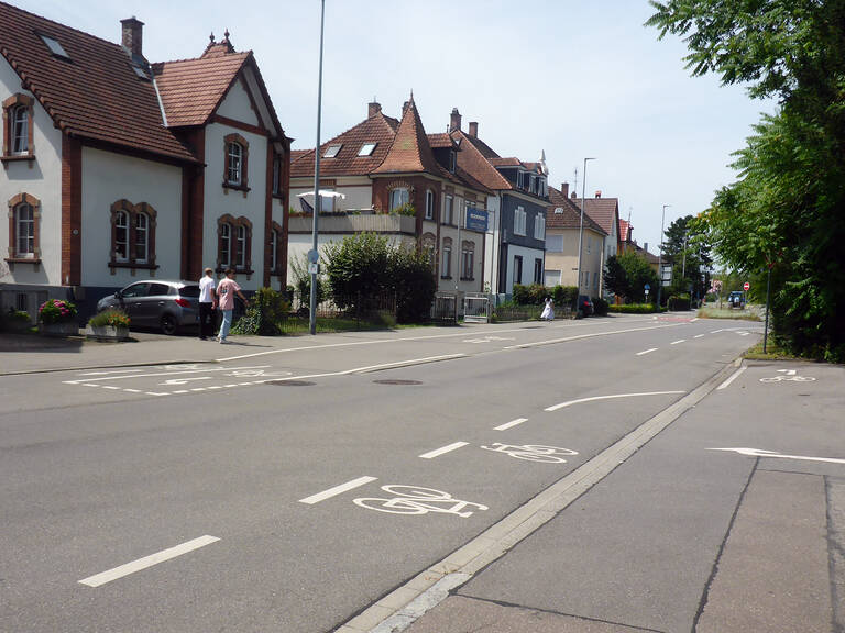 Eine ruhige Straße mit Fahrradwegmarkierungen und mehreren Häusern im traditionellen Stil.