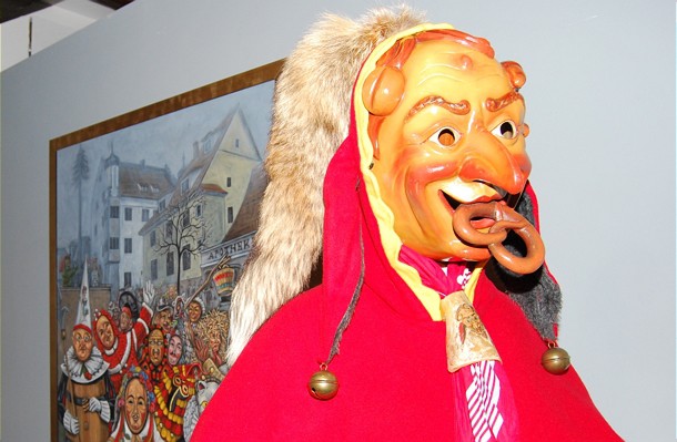  Traditionelles Kostüm mit Maske, im Hintergrund ist ein gemaltes Bild von mehreren verkleideten Personen | Foto: Stadtverwaltung Radolfzell/ml 