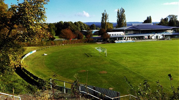  Rasen Fußballplatz von oben, im Hintergrund ein Gebäude und rechts im Bild Bäume 
